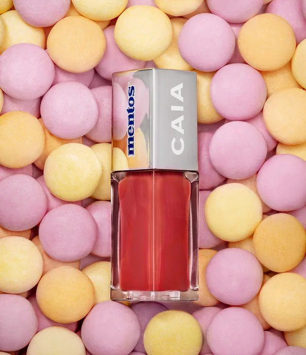 CAIA x Mentos läppglans med silverlock bland rosa, gula och orange Mentos.